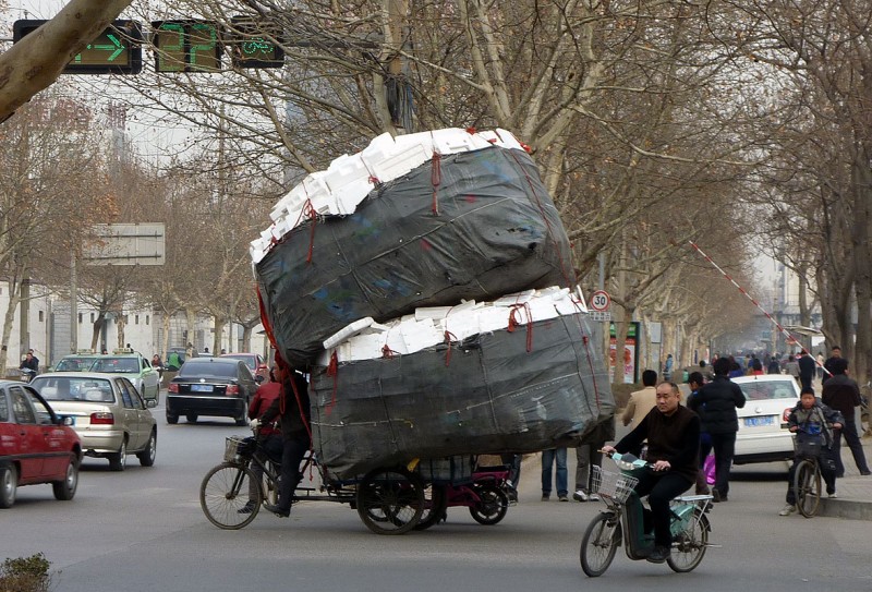 chinese man on three wheel bike carrying huge load