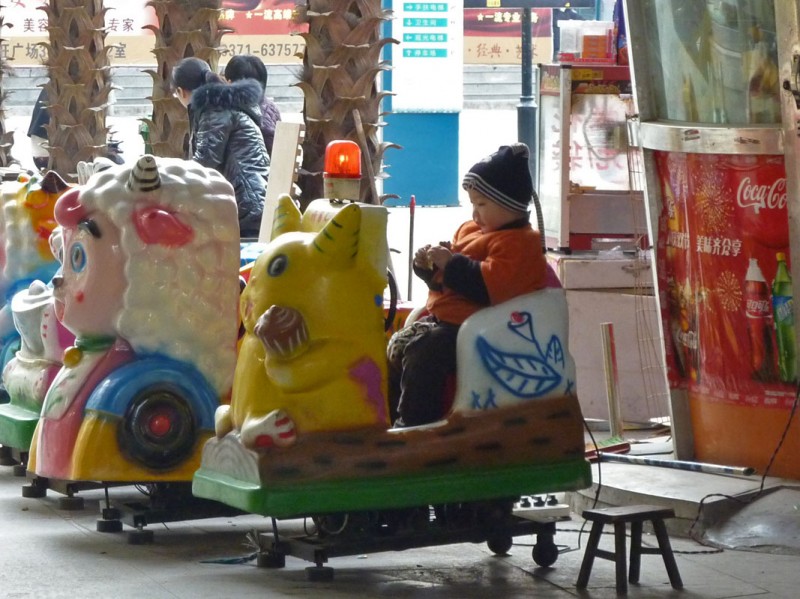 Chinese boy eating french fries on a pikachu ride